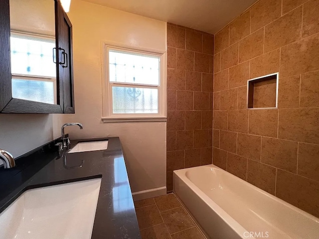 bathroom with tile patterned flooring, double vanity, baseboards, and a sink