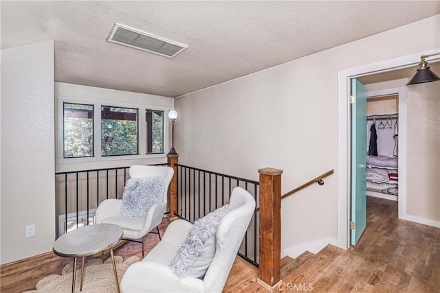 37751 Foxfield Rd, Angelus Oaks, CA 92305 - living area with visible vents, an upstairs landing, a textured ceiling, wood finished floors, and baseboards