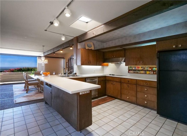 kitchen with under cabinet range hood, light countertops, a peninsula, black appliances, and a sink