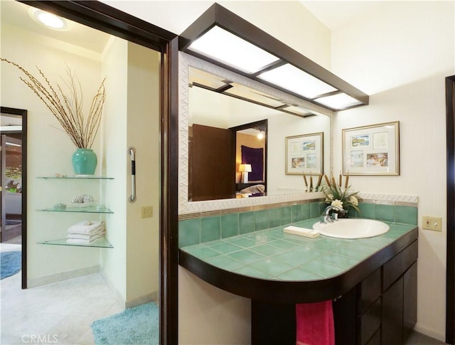 ensuite bathroom featuring ensuite bath, baseboards, tile patterned floors, and a sink