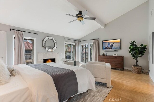 bedroom with beam ceiling, a ceiling fan, a fireplace, light wood finished floors, and access to exterior