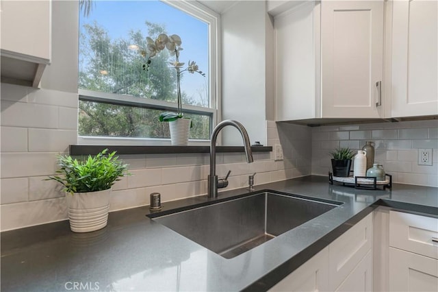 details with dark countertops, white cabinetry, tasteful backsplash, and a sink