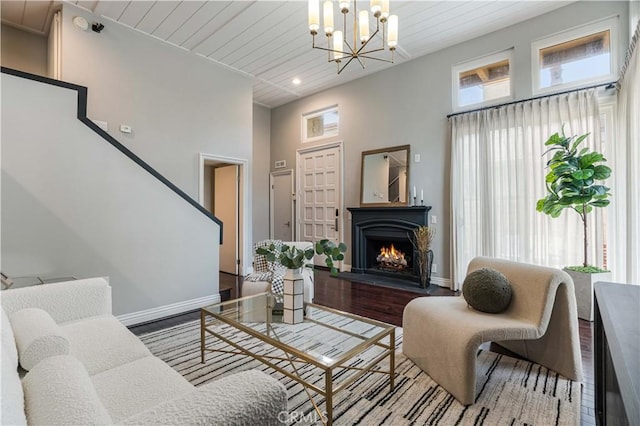 living room with wooden ceiling, a notable chandelier, wood finished floors, and baseboards