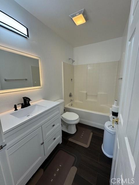 bathroom featuring tub / shower combination, toilet, vanity, and wood finished floors