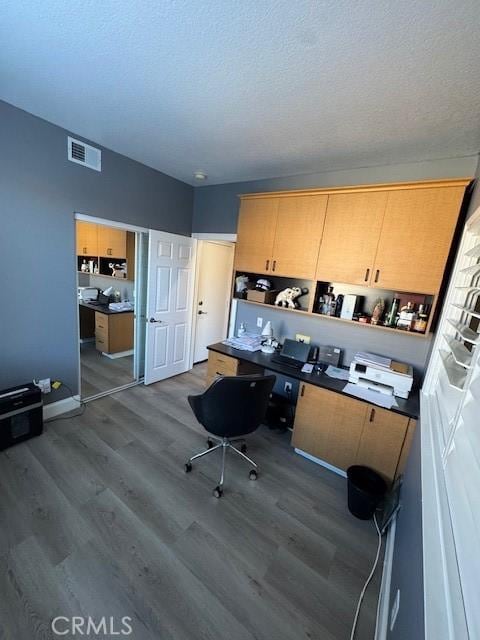 office space featuring wood finished floors, visible vents, and a textured ceiling