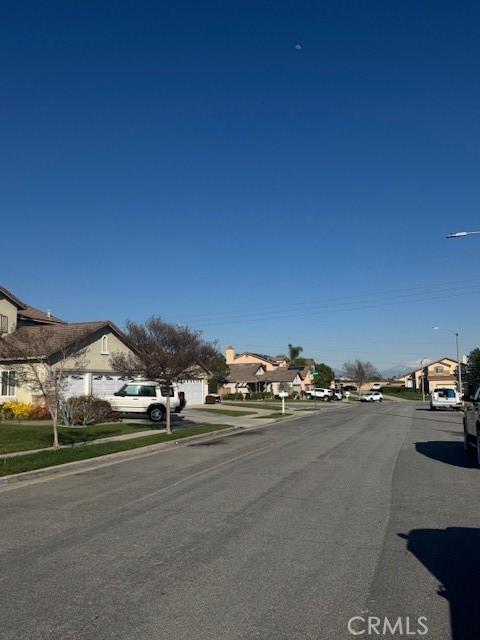 view of road featuring sidewalks, a residential view, curbs, and street lighting