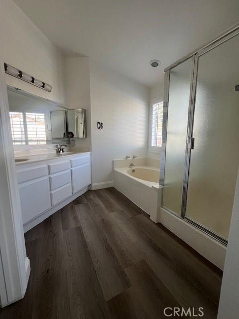 full bath featuring a shower stall, wood finished floors, vanity, and a bath