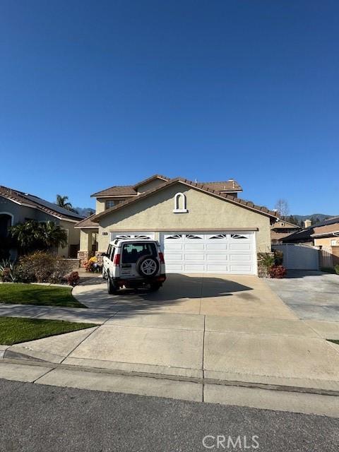 view of front of property featuring stucco siding, driveway, and a garage