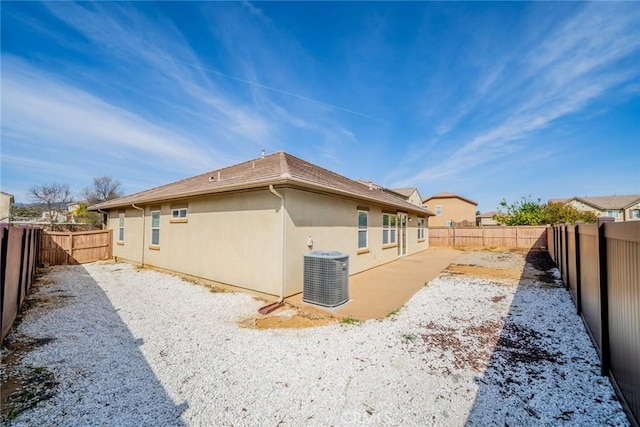 rear view of house featuring a fenced backyard, stucco siding, and central AC