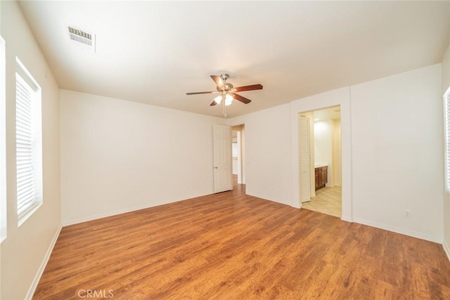 unfurnished bedroom with baseboards, light wood-style flooring, visible vents, and multiple windows