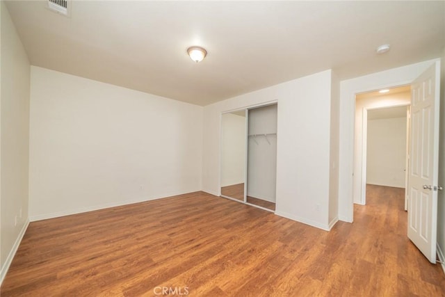 unfurnished bedroom with baseboards, a closet, visible vents, and light wood-style floors