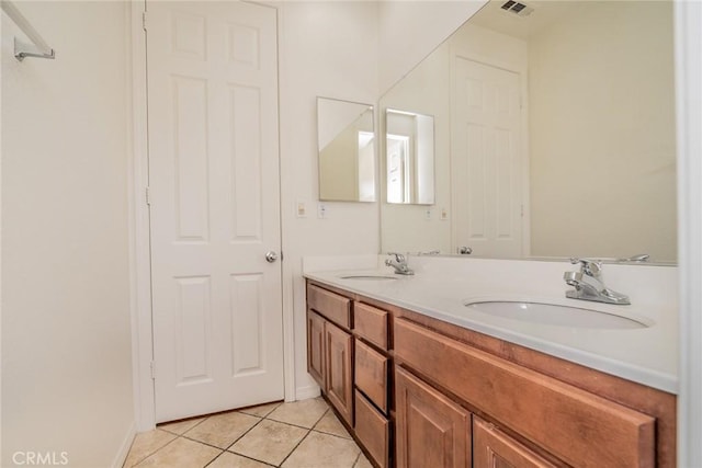 bathroom featuring baseboards, double vanity, a sink, and tile patterned flooring