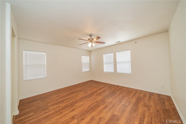 spare room featuring baseboards, wood finished floors, and a ceiling fan