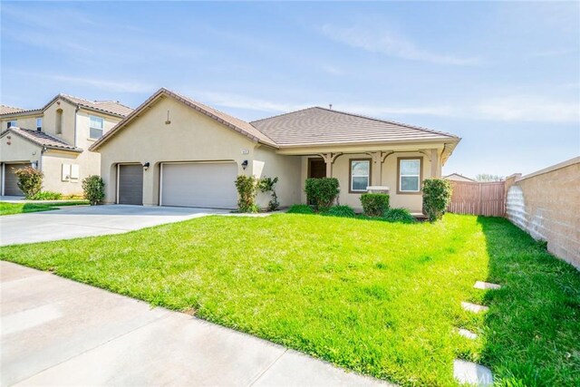 view of front of house with concrete driveway, stucco siding, fence, an attached garage, and a front yard