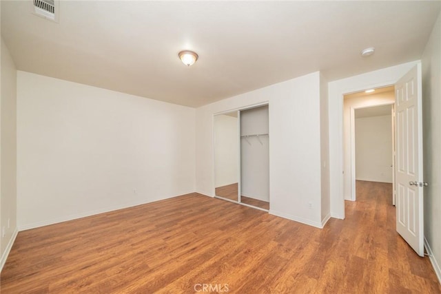 unfurnished bedroom featuring a closet, baseboards, visible vents, and light wood-type flooring