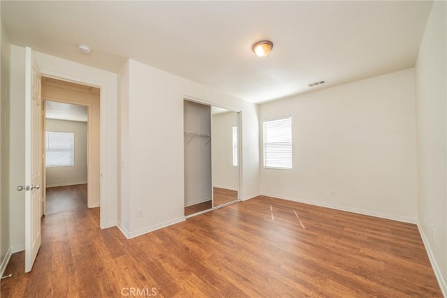 unfurnished bedroom with a closet, baseboards, light wood-style floors, and visible vents