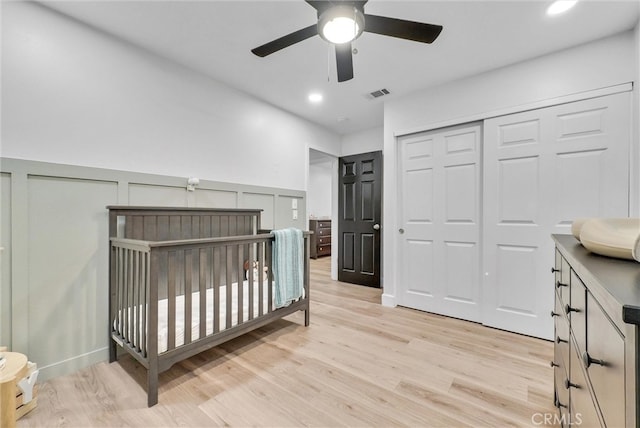 bedroom featuring a wainscoted wall, a closet, visible vents, and light wood finished floors