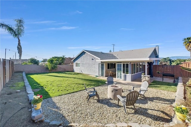 rear view of house featuring a patio area, a fenced backyard, and an outdoor fire pit