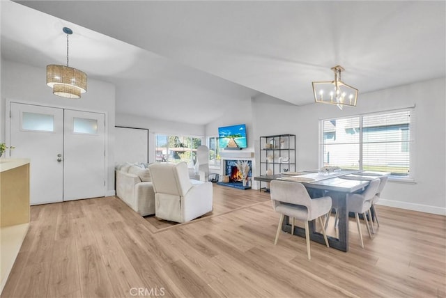 dining room with light wood-style flooring, lofted ceiling, baseboards, and a chandelier