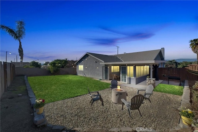 rear view of property with a yard, a patio, a fire pit, and a fenced backyard