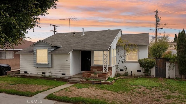 bungalow-style house with crawl space, a shingled roof, a yard, and fence