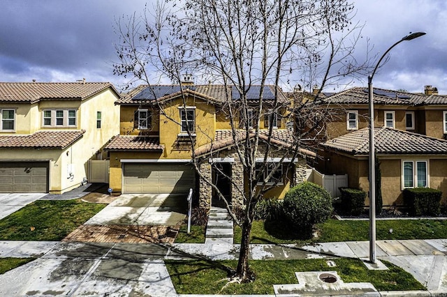 mediterranean / spanish-style house featuring driveway, stucco siding, a garage, a tile roof, and roof mounted solar panels