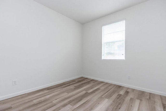 unfurnished room with baseboards and light wood-style flooring