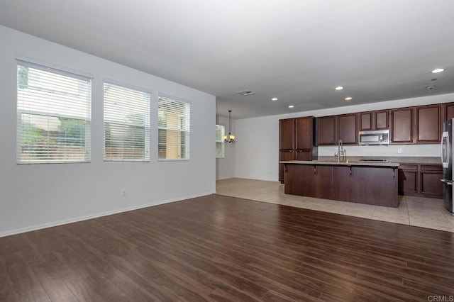 kitchen featuring open floor plan, light wood-style flooring, stainless steel appliances, and a kitchen island with sink