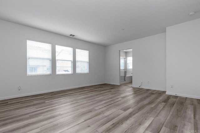 spare room with visible vents, light wood-style flooring, and baseboards