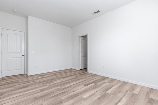 empty room featuring visible vents, baseboards, and light wood-style floors