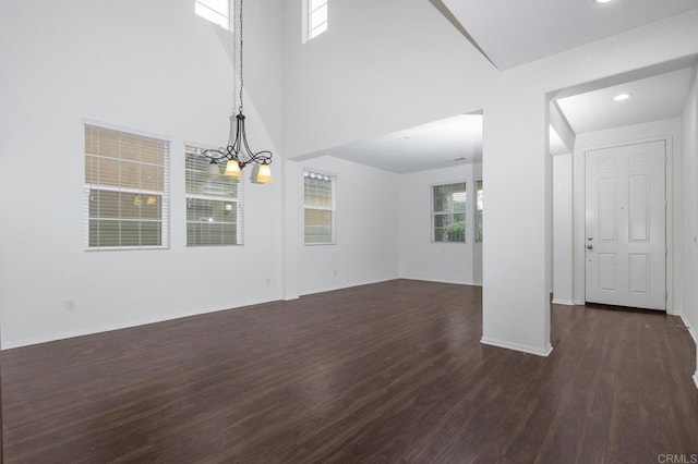 interior space featuring a wealth of natural light, baseboards, dark wood finished floors, and a towering ceiling