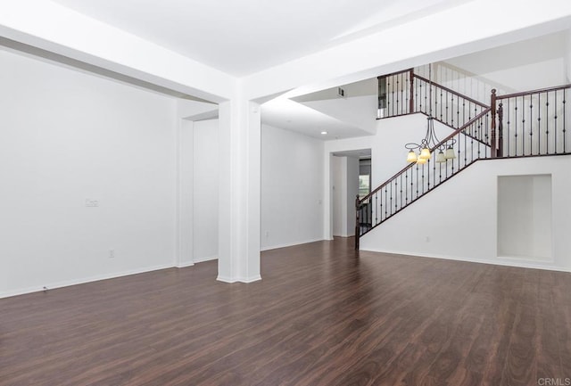 unfurnished living room featuring dark wood-type flooring, stairway, and baseboards