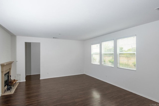 unfurnished living room with a fireplace, visible vents, dark wood-style floors, and baseboards