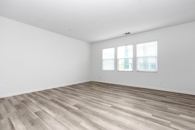 spare room featuring visible vents, light wood-type flooring, and baseboards