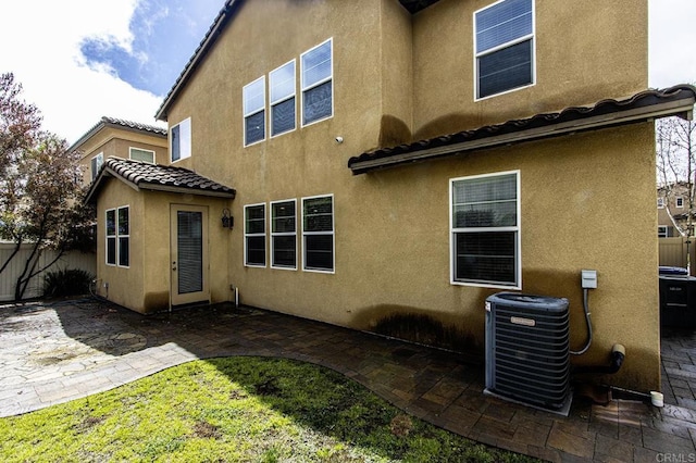 back of house with central AC unit, fence, stucco siding, a tile roof, and a patio area