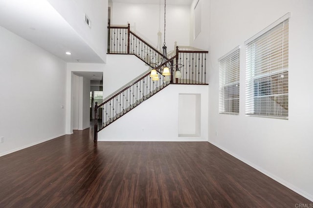 unfurnished living room with visible vents, a high ceiling, wood finished floors, and stairs