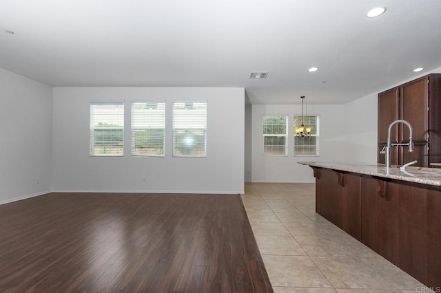 unfurnished living room with visible vents, light wood-type flooring, recessed lighting, an inviting chandelier, and a sink