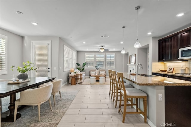 kitchen featuring light stone countertops, a breakfast bar, a sink, appliances with stainless steel finishes, and tasteful backsplash