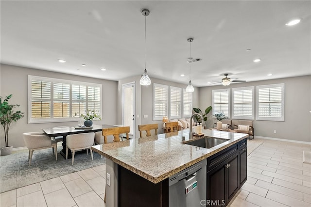 kitchen featuring open floor plan, an island with sink, stainless steel dishwasher, hanging light fixtures, and a sink