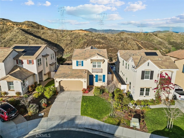 view of front of property featuring stucco siding, a residential view, concrete driveway, and a mountain view