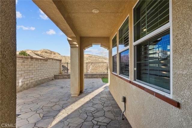 view of patio with a mountain view and fence