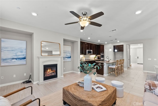 living room featuring visible vents, recessed lighting, a ceiling fan, and a glass covered fireplace