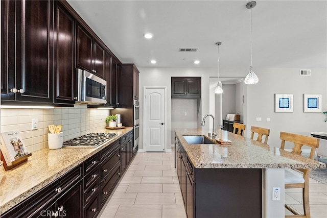 kitchen with visible vents, appliances with stainless steel finishes, a kitchen bar, and a sink