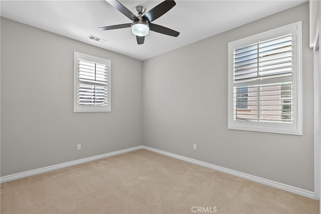 empty room with visible vents, light colored carpet, baseboards, and a ceiling fan