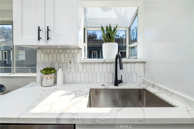 24877 Nueva Vista Dr Unit 23, Laguna Niguel, CA 92677 - kitchen featuring backsplash, light stone countertops, white cabinetry, and a sink