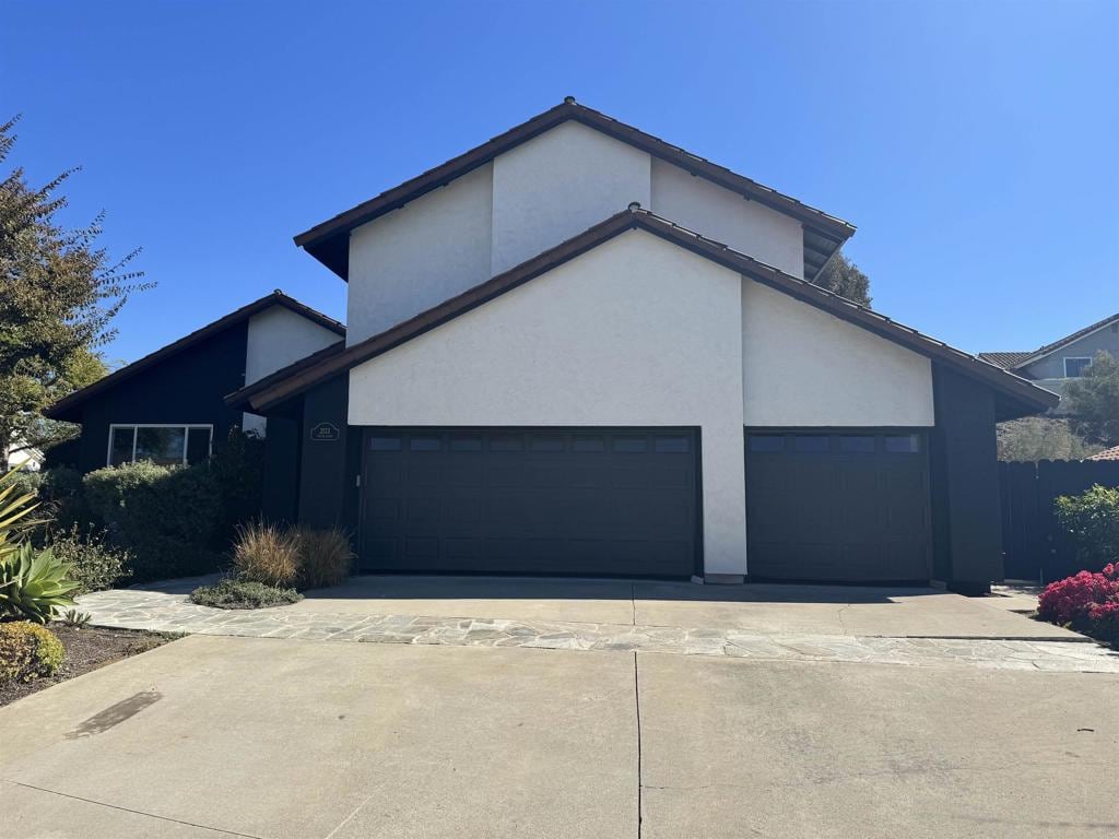 view of front of house featuring a garage, concrete driveway, and stucco siding