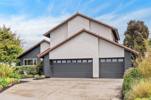 view of front of property with a tiled roof, stucco siding, driveway, and an attached garage