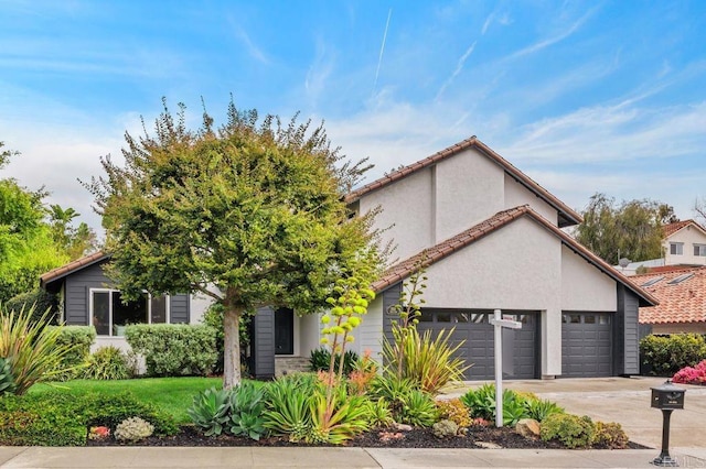 view of front of house with stucco siding, a garage, driveway, and a tiled roof