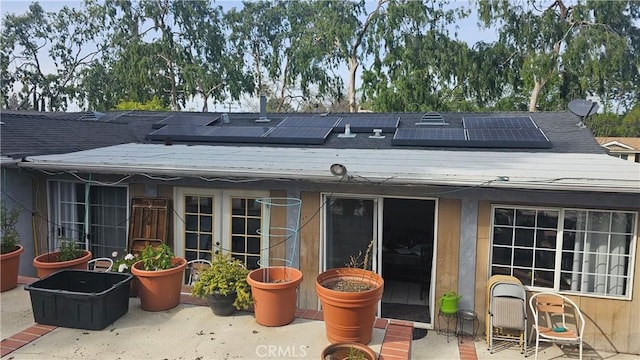 back of property with french doors, a patio, and roof mounted solar panels