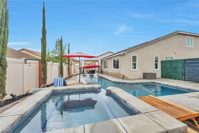 view of pool featuring a patio area, a pool with connected hot tub, and a fenced backyard